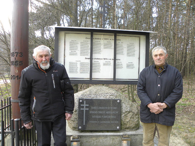 Julian Jastrzębski i Antoni Dąbrowski przy tablicy z nazwiskami zmarłych podczas epidemii cholery.