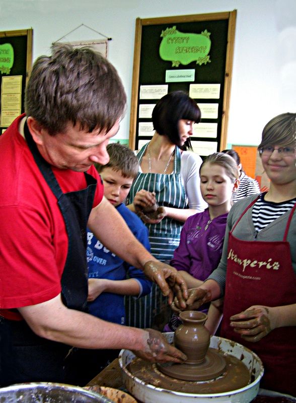 Piotr Skiba pokazuje uczniom w jaki sposób na kole garncarskim z niekształtnej gliniastej masy uformować dzbanek. Fot. Arch. ZS w Zagoździu