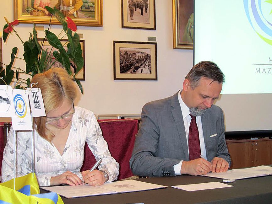 Burmistrz Marcin Jakubowski podpisuje umowę z Anną Saliną z Instytutu Historycznego PAN. Fot. B. Nowotniak