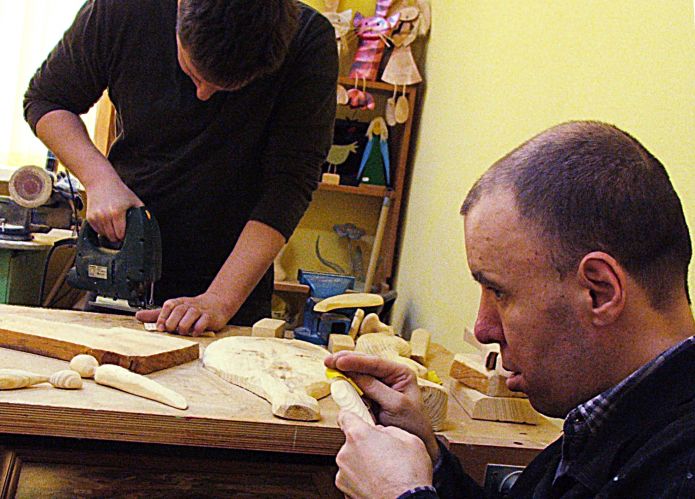 Jeden z podopiecznych WTZ w Łukowie, Grzegorz (z prawej), w pracowni stolarskiej przygotowuje elementy postaci drewnianych kotków. Fot. PGL